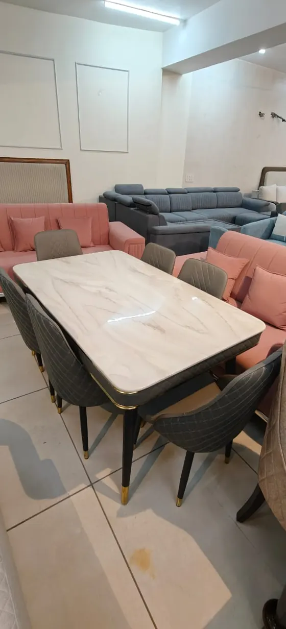 A stone-top dining table with pink and grey chairs on the showroom floor